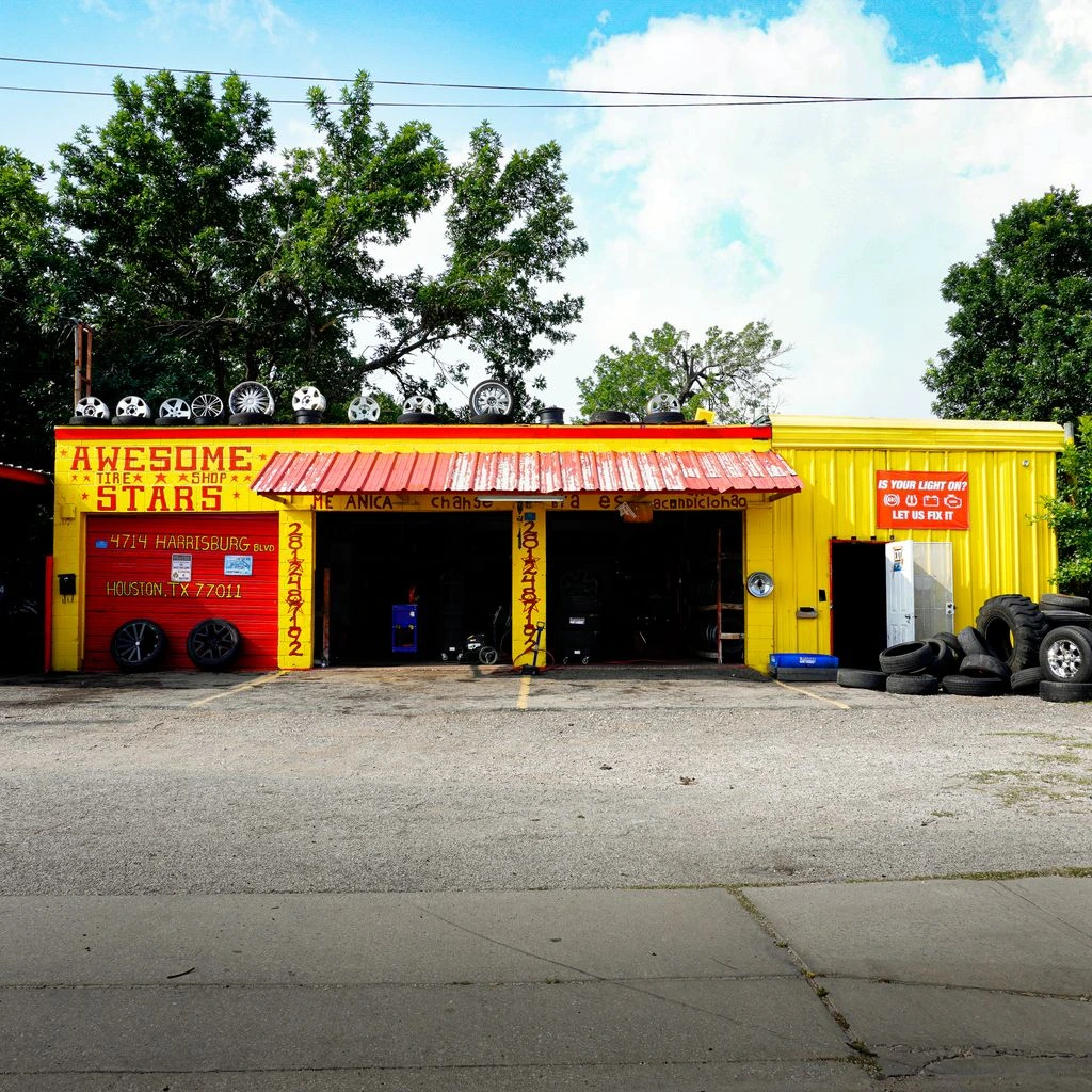 Exterior of a Tire Town store at dusk with three open service bays.
